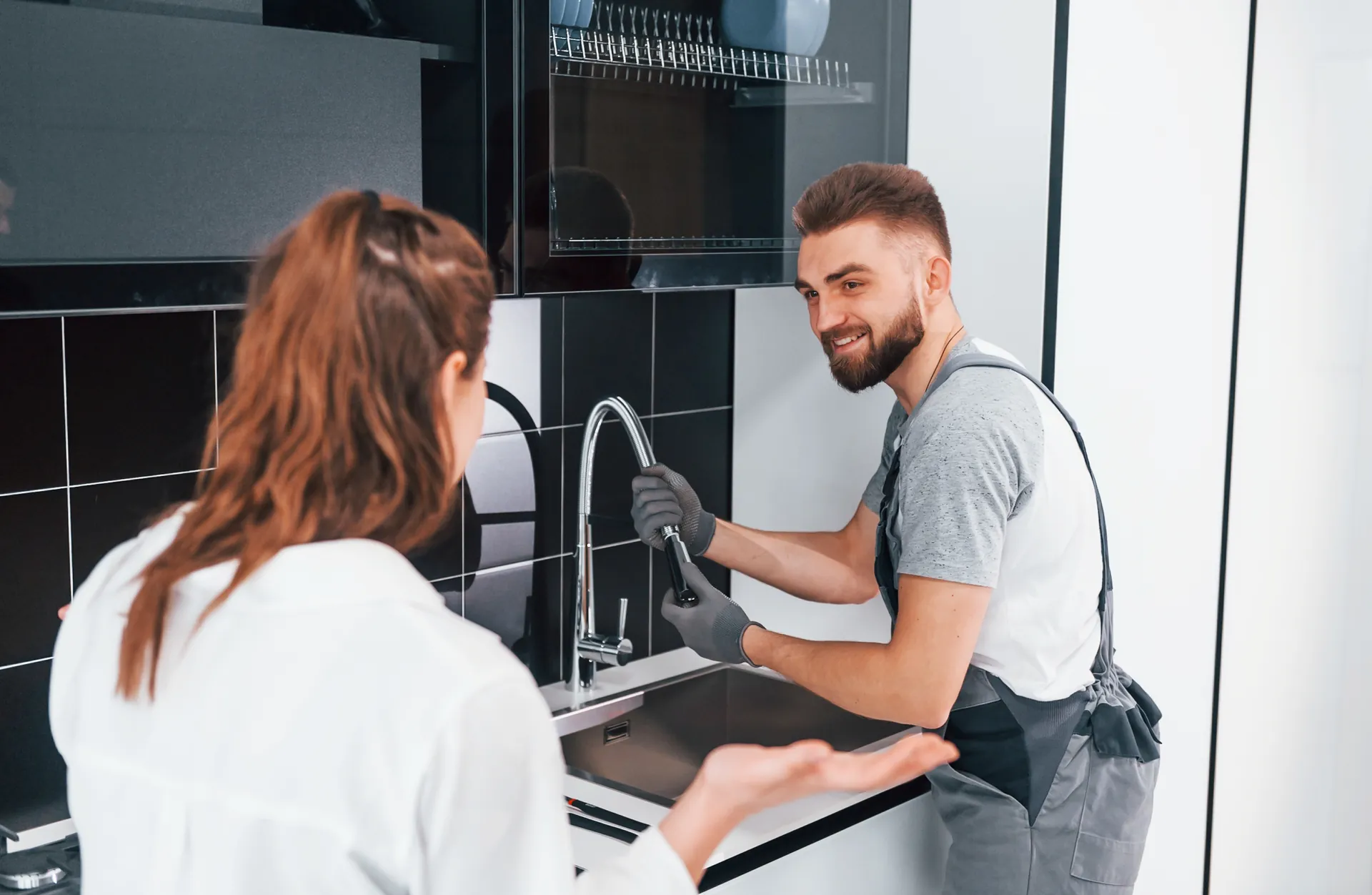 Plumber repairing a sink in a modern kitchen